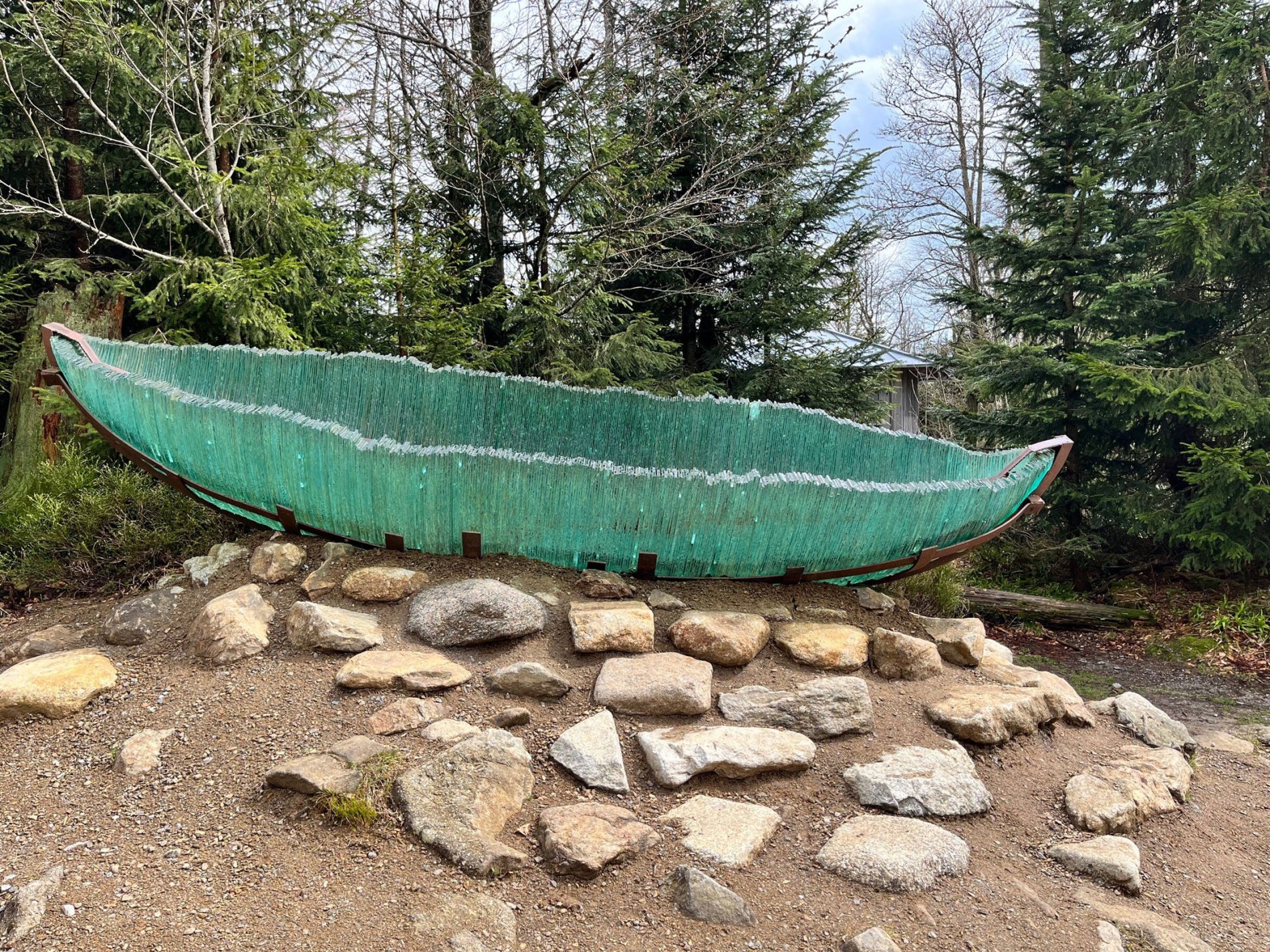 Die Glasarche getragen von einer starken Holzhand inmitten des Bayerischen Waldes am Lusen.