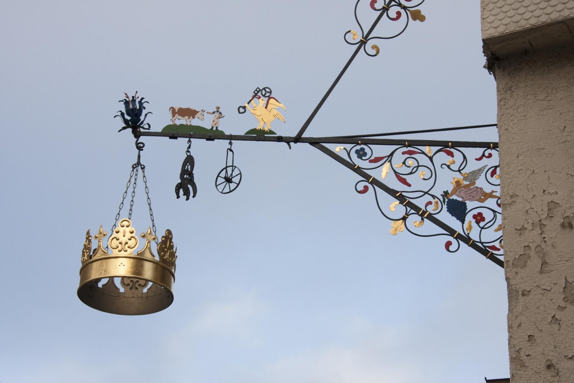 Das Gasthaus Krone in Münsingen im Biosphärengebiet Schwäbische Alb. An einer Hauswand hängt ein Nasenschild mit einer goldenen Krone. Es ist kunstvoll verziert.
