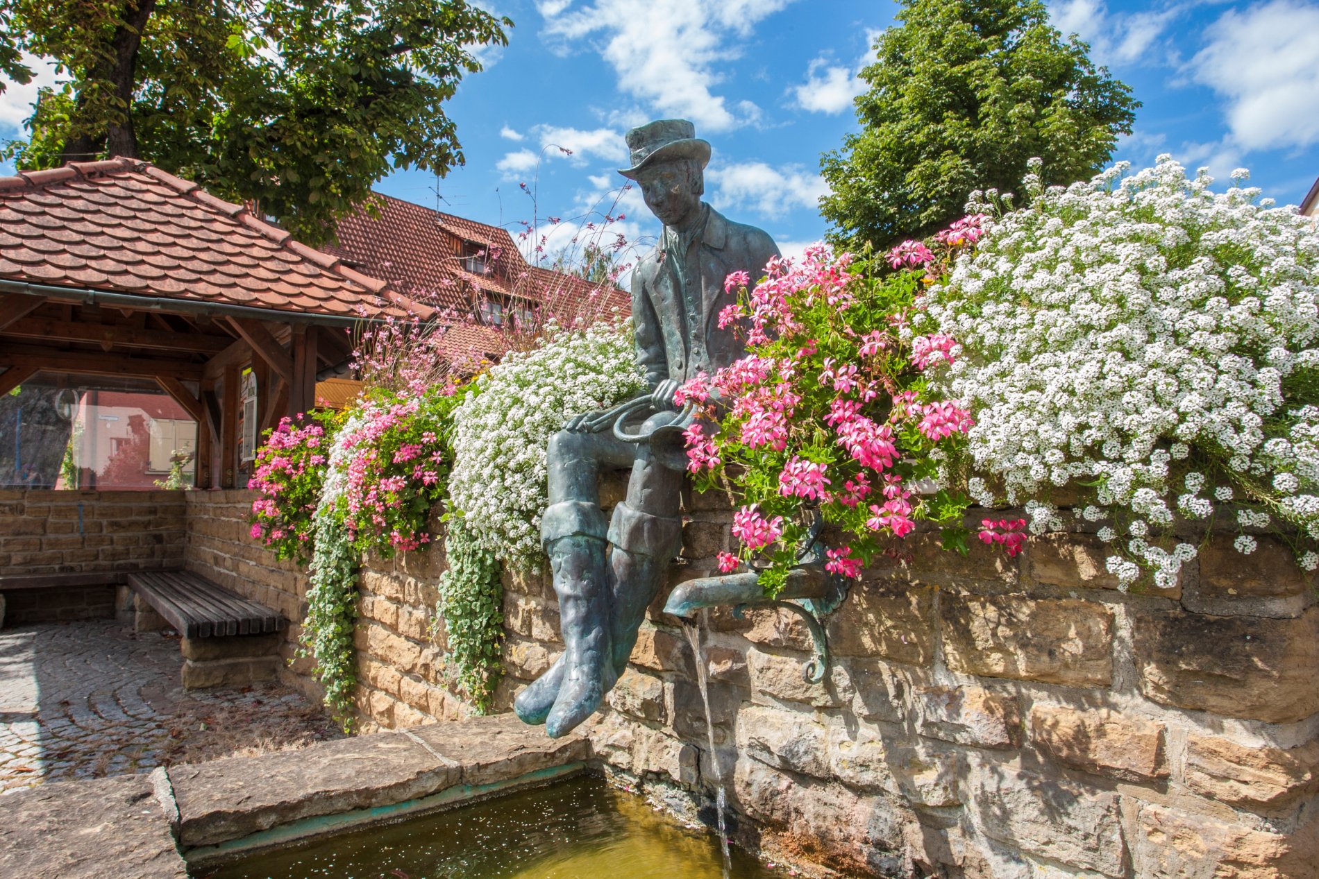 Brunnen mit Blumen und der Skulptur eines Mannes