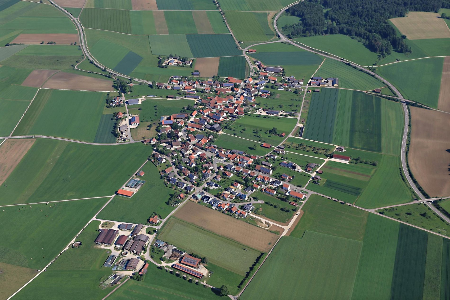 Ein Luftbild von einem Dorf. Ringsherum sind Felder.