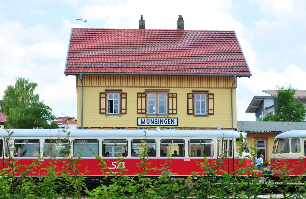 Im Vordergrund ein roter Schienenbus, dahinter ein historisches Gebäude