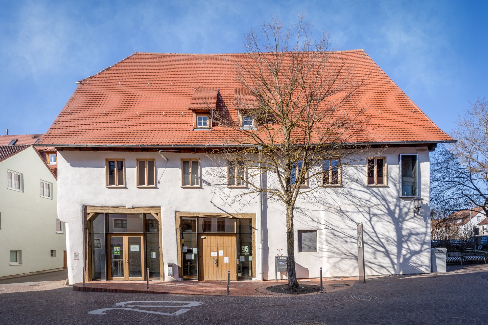 Zehntscheuer und Stiftungspflegefruchtkasten in Münsingen im Biosphärengebiet Schwäbische Alb. Ein Gebäude mit zwei großen Türen. Türen und Fenster haben Holzrahmen.