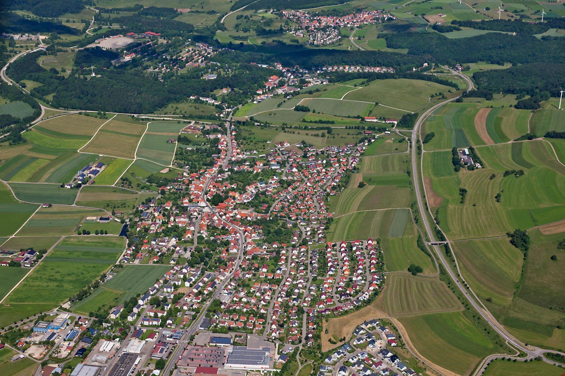 Ein Luftbild einer Stadt. Ringsherum sind Felder und Wälder.