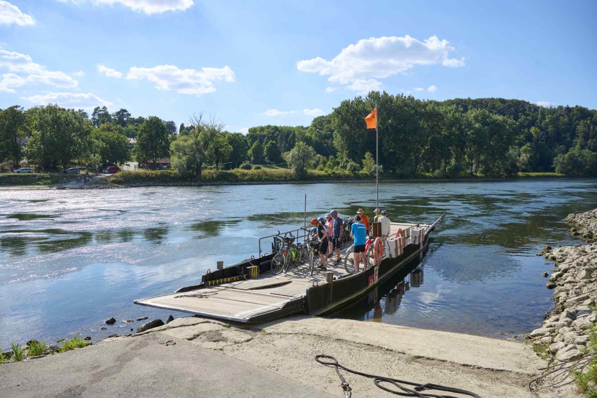 Auf der Seilfähre bei Weltenburg sind mehrere Personen und Fahrräder, die ans andere Ufer gebracht werden.