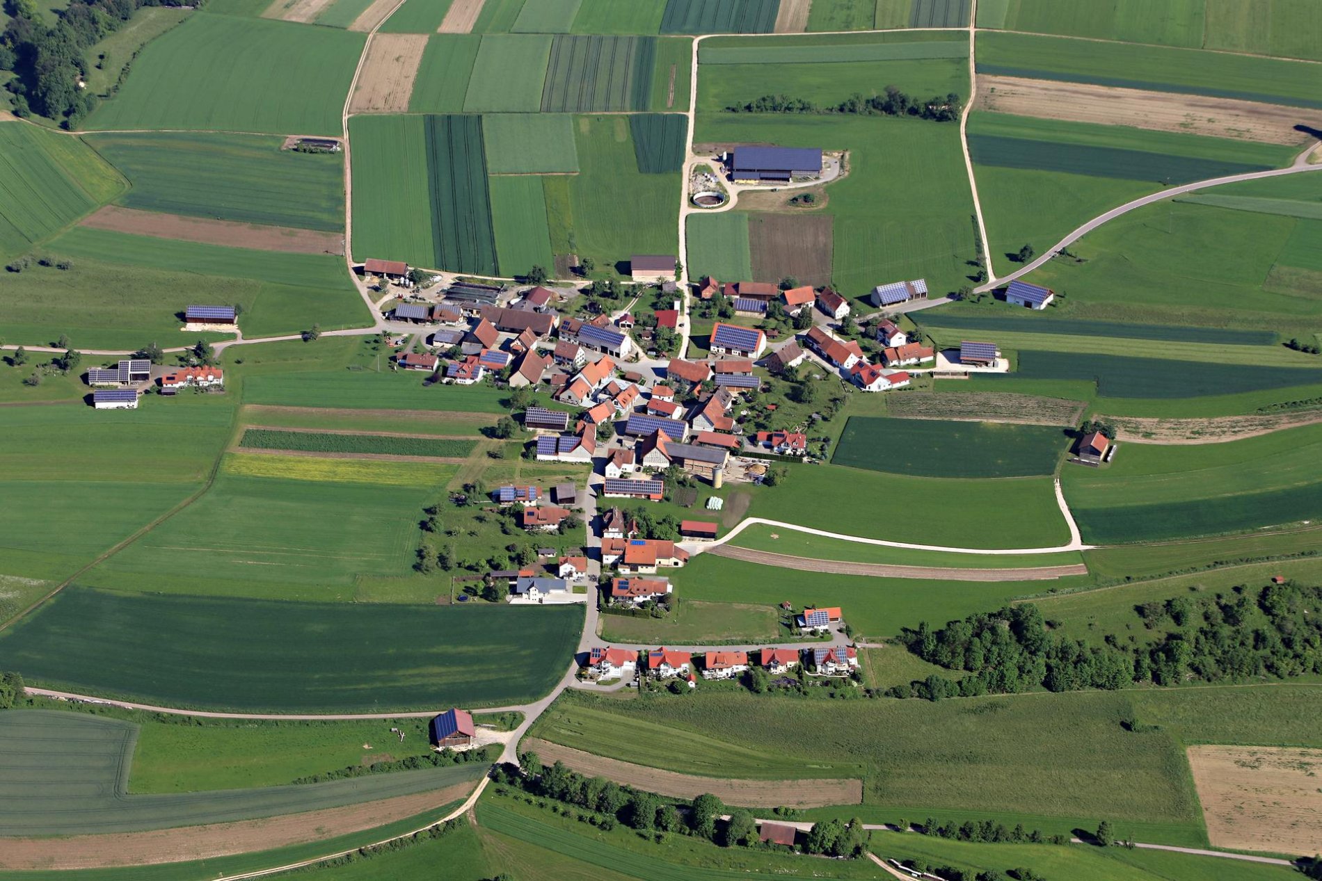 Ein Luftbild eines kelinen Dorfs. Ringsherum sind Felder.