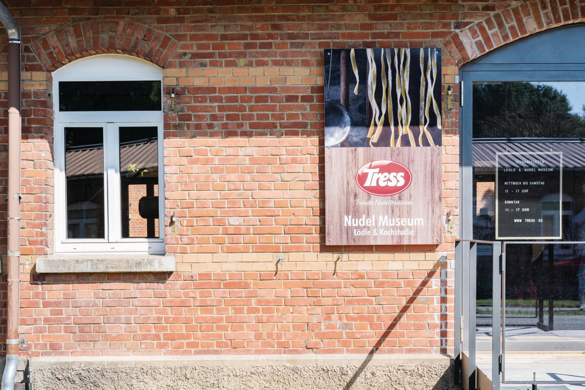 Tress Manufaktur im Albgut - Altes Lager am Rande des ehemaligen Truppenübungsplatz in Münsingen im Biosphärengebiet Schwäbische Alb. An einem Backsteinhaus ist ein Schild mit einem Bild mit Nudeln einer Aufschrift.