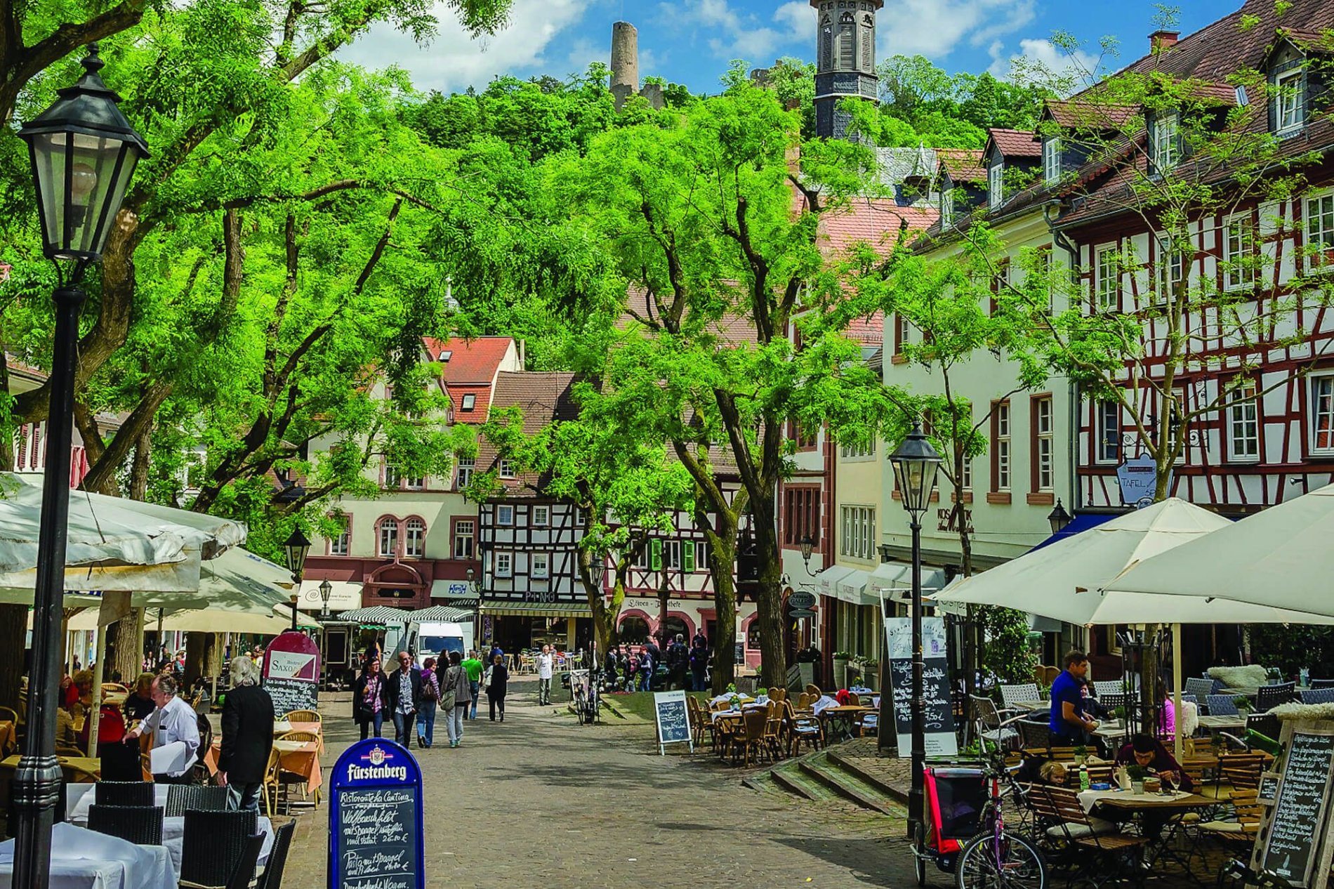 Marktplatz mit Personen und den grünen Bäumen.
