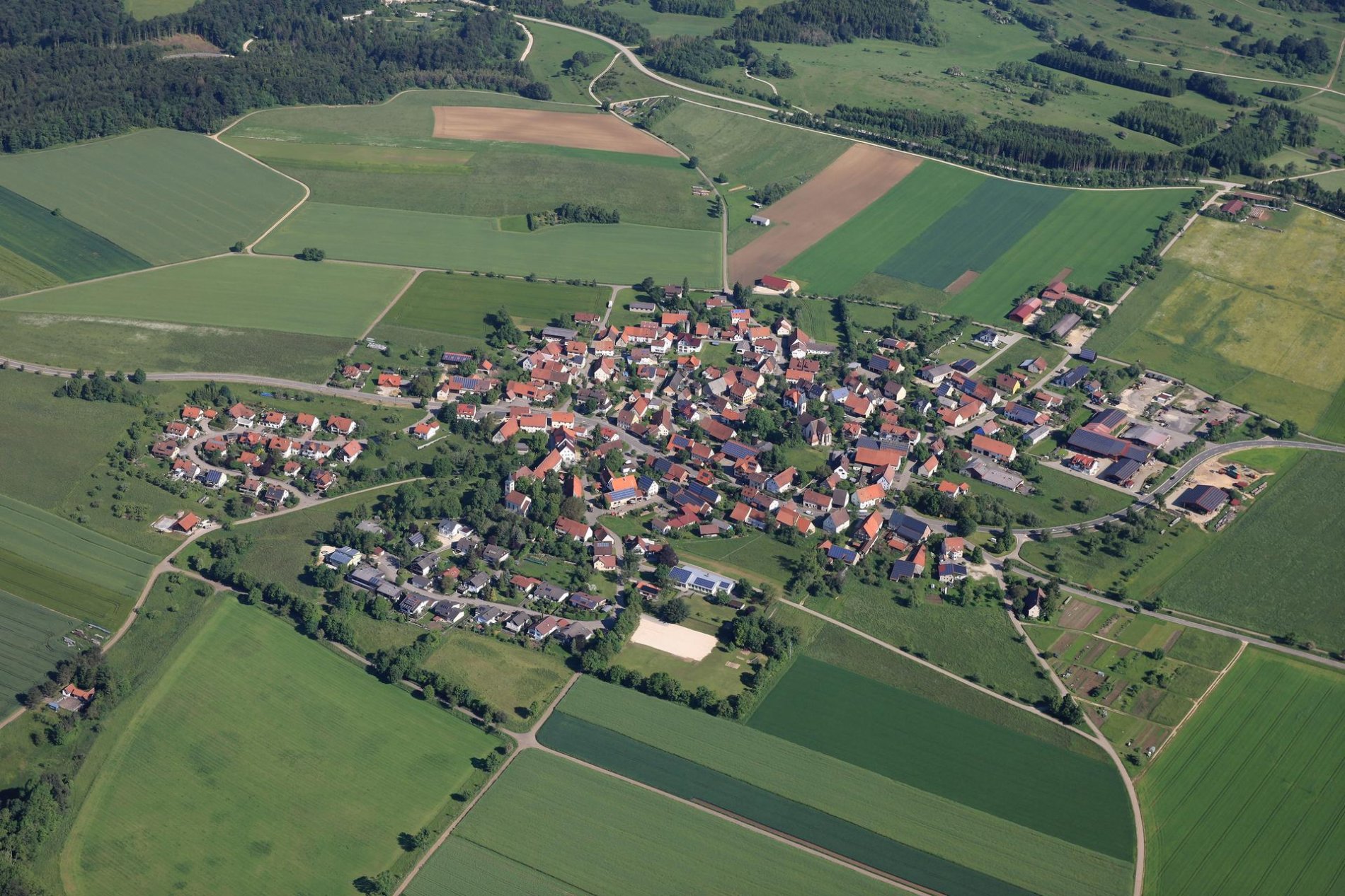 Ein Luftbild von einem Dorf. Ringsherum sind Felder.