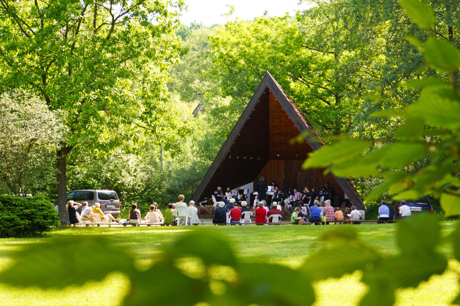 Gäste sitzen auf Bänken und hören dem Konzert des Musikvereins Obertalheim im Musikpavillon zu
