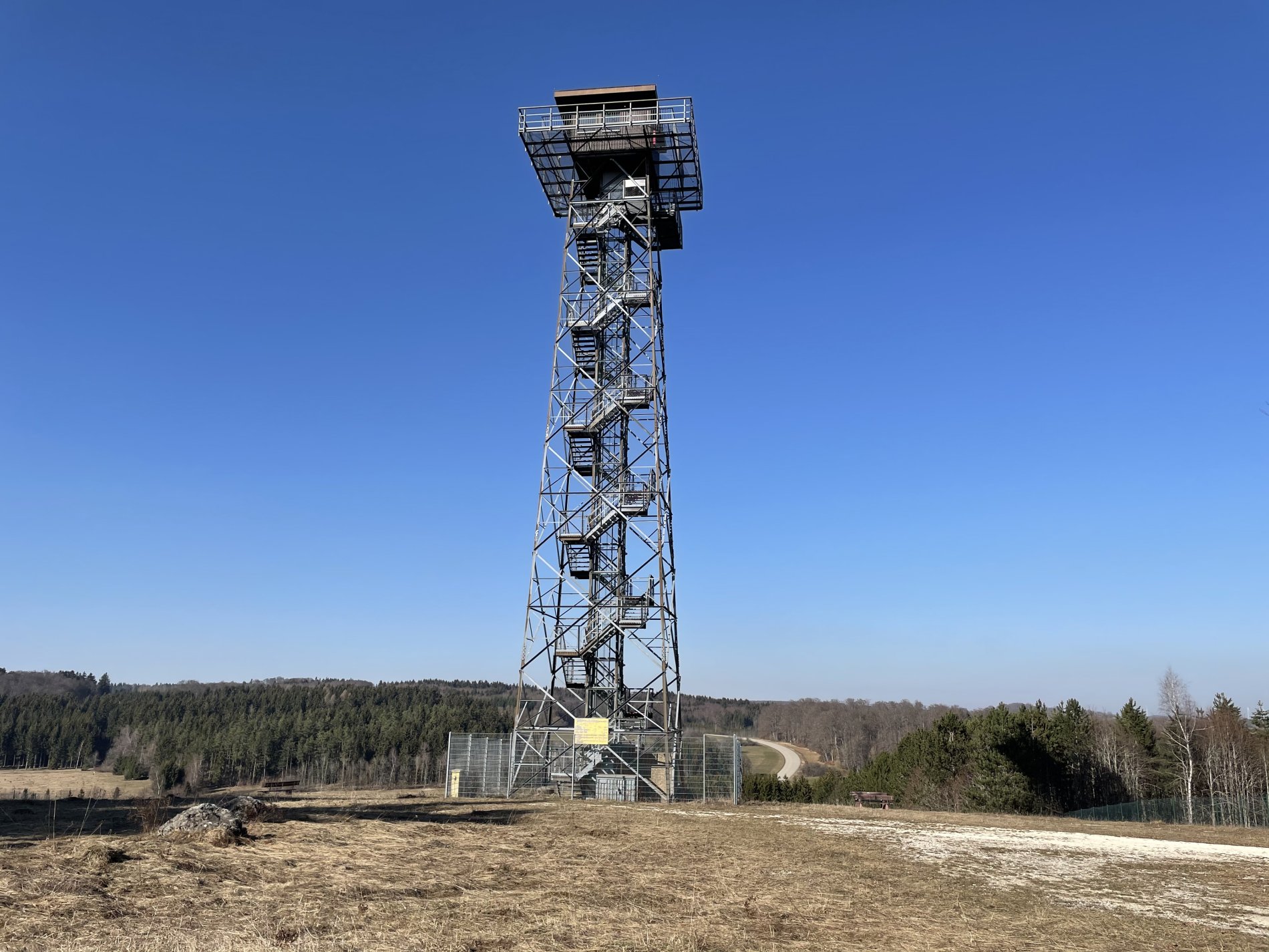 Der Turm Heroldstatt auf dem ehemaligen Truppenübungsplatz Münsingen im Biosphärengebiet Schwäbische Alb. Ein Stahlgitterturm im Frühling. Oben ist ein kleines Häuschen und eine Aussichtsplattform.