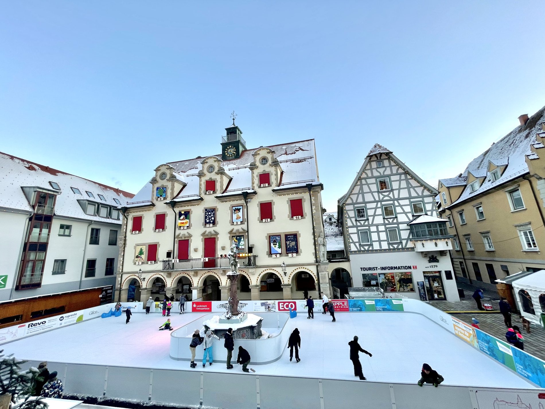 Eisbahn mit historischem Rathaus im Hintergrund.