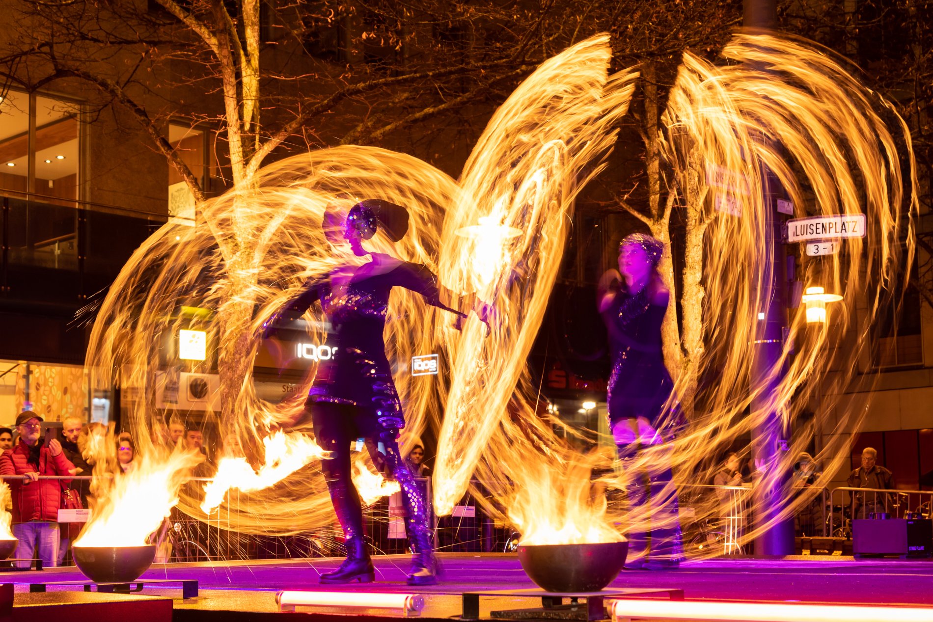 Feuershow, zwei Personen die mit brennenden Fackeln große feurige Kreise um sich herum ziehen.