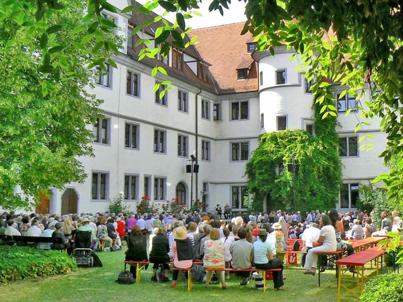 Viele Menschen sitzen auf Bierbänken auf dem Tübinger Bücherfest