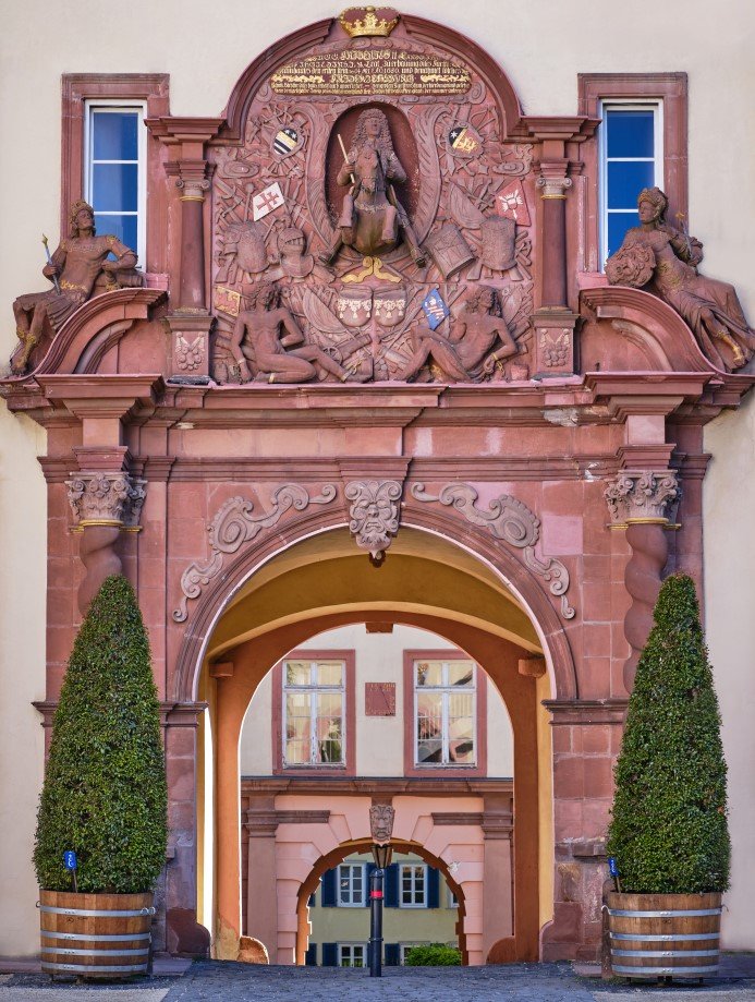 Ein Portal im Schloss Bad Homburg zeigt Friedrich den II. als Reiter. Zwei Kübelpflanzen sind links und rechts des Portals aufgestellt. Man blickt durch zwei Rundbögen auf den Oberen Schlosshof.