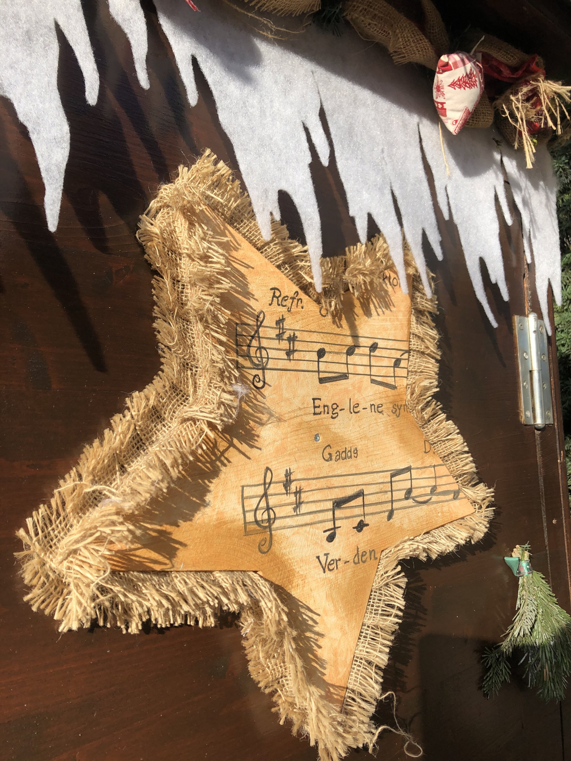 Stern aus Notenblatt hängt an weihnachtlich dekorierter Hütte