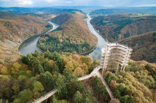 Treetop walk with high observation tower in the middle of the forest with a view of a river bend