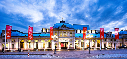 Festspielhaus Baden-Baden in der Dämmerung, im Vordergrund rote Fahnen
