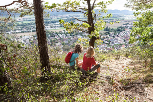 Zwei Menschen sitzen und blicken auf ein Tal.